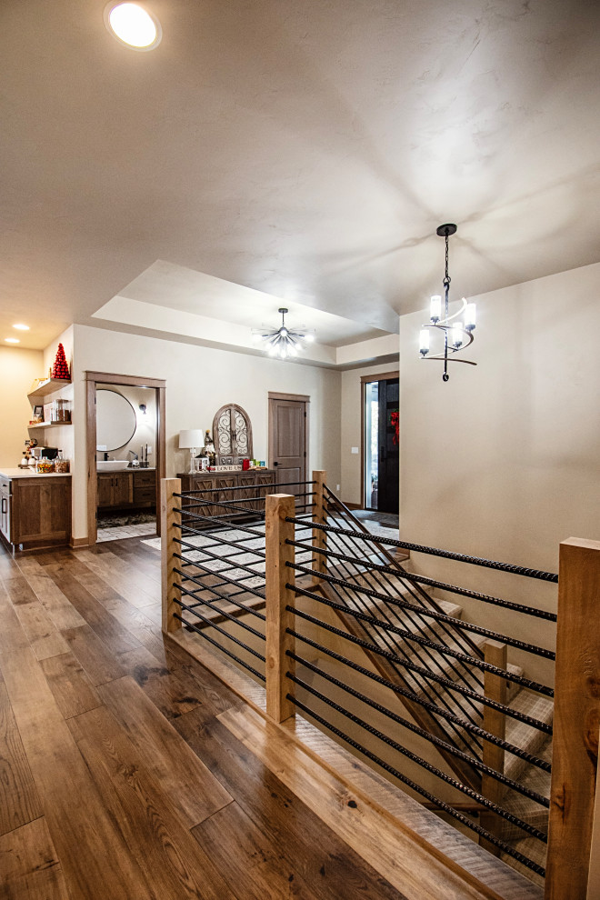 Large mountain style medium tone wood floor, multicolored floor and tray ceiling hallway photo with beige walls