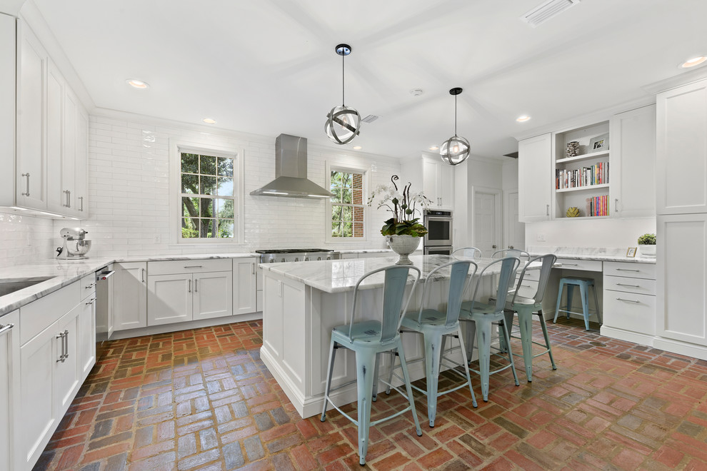 Inspiration for a transitional u-shaped kitchen in Jacksonville with shaker cabinets, white cabinets, white splashback, with island, red floor, an undermount sink, stainless steel appliances, brick floors and white benchtop.