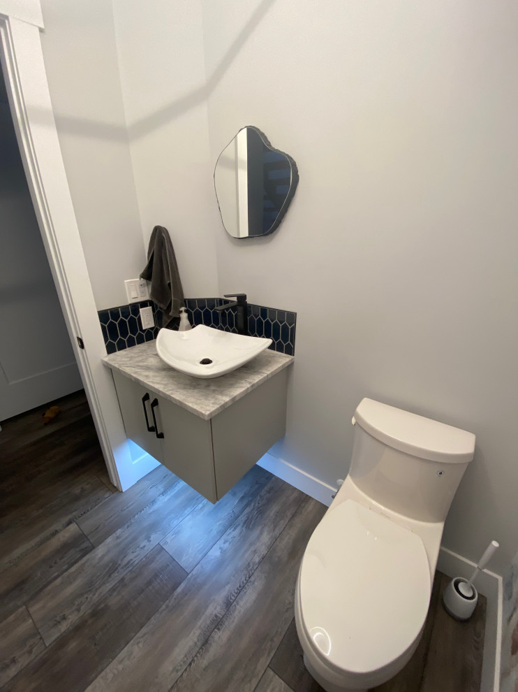 Inspiration for a small contemporary blue tile and ceramic tile vinyl floor, brown floor and wallpaper powder room remodel in Calgary with flat-panel cabinets, gray cabinets, a one-piece toilet, blue walls, an undermount sink, granite countertops, white countertops and a built-in vanity