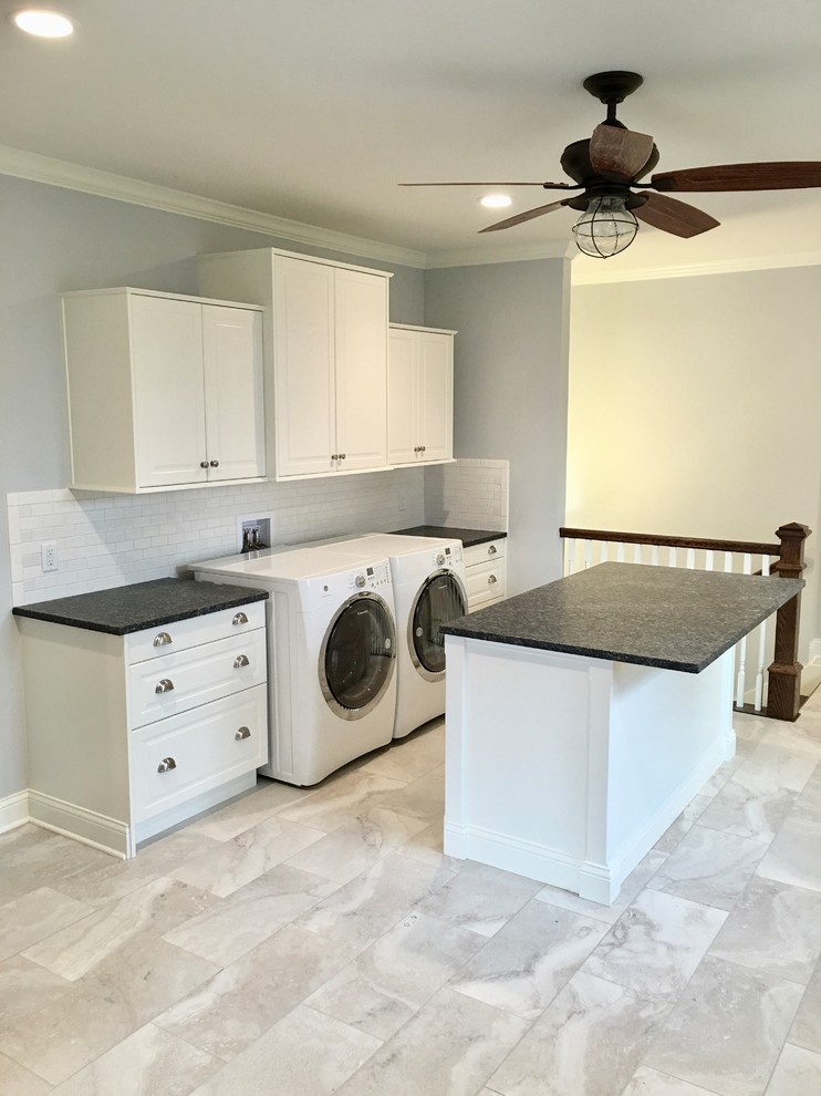 Large country galley utility room in Austin with raised-panel cabinets, white cabinets, granite benchtops, grey walls, porcelain floors, a side-by-side washer and dryer, multi-coloured floor and blue benchtop.