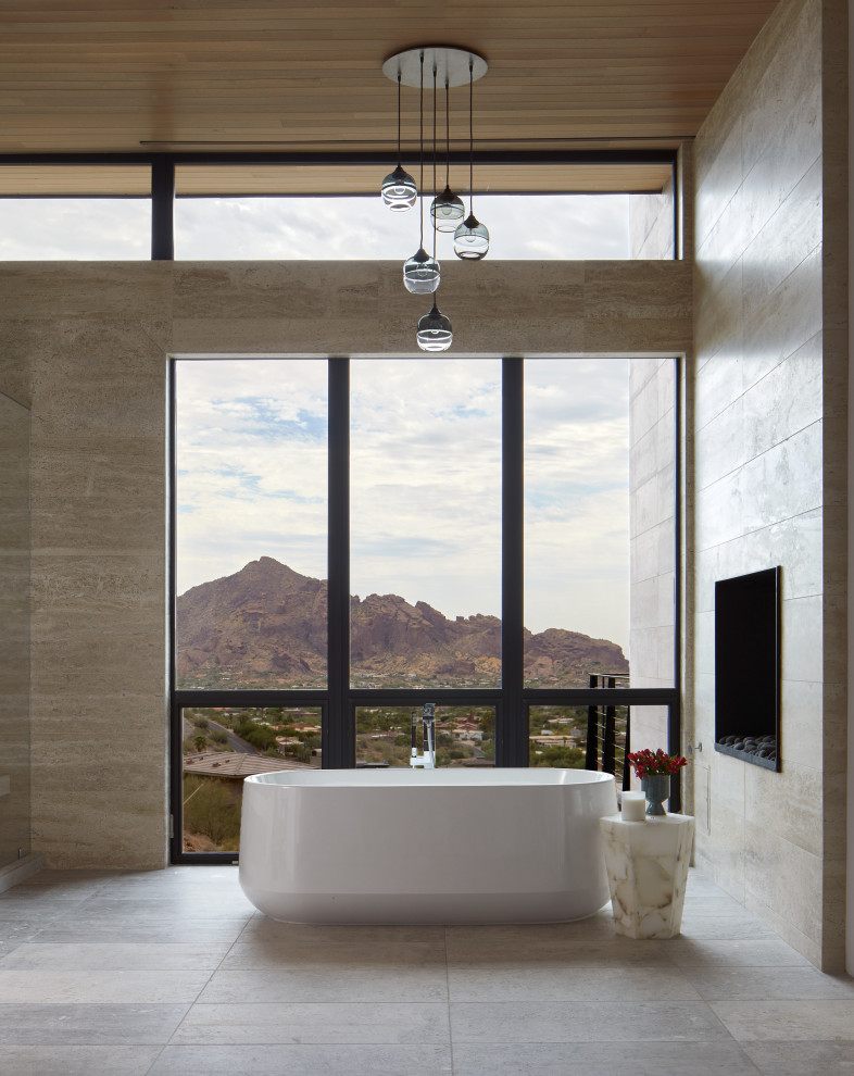 Expansive modern master bathroom in Phoenix with a freestanding tub, limestone floors and wood.