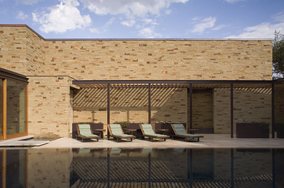 Large contemporary courtyard rectangular infinity pool in Austin with tile.