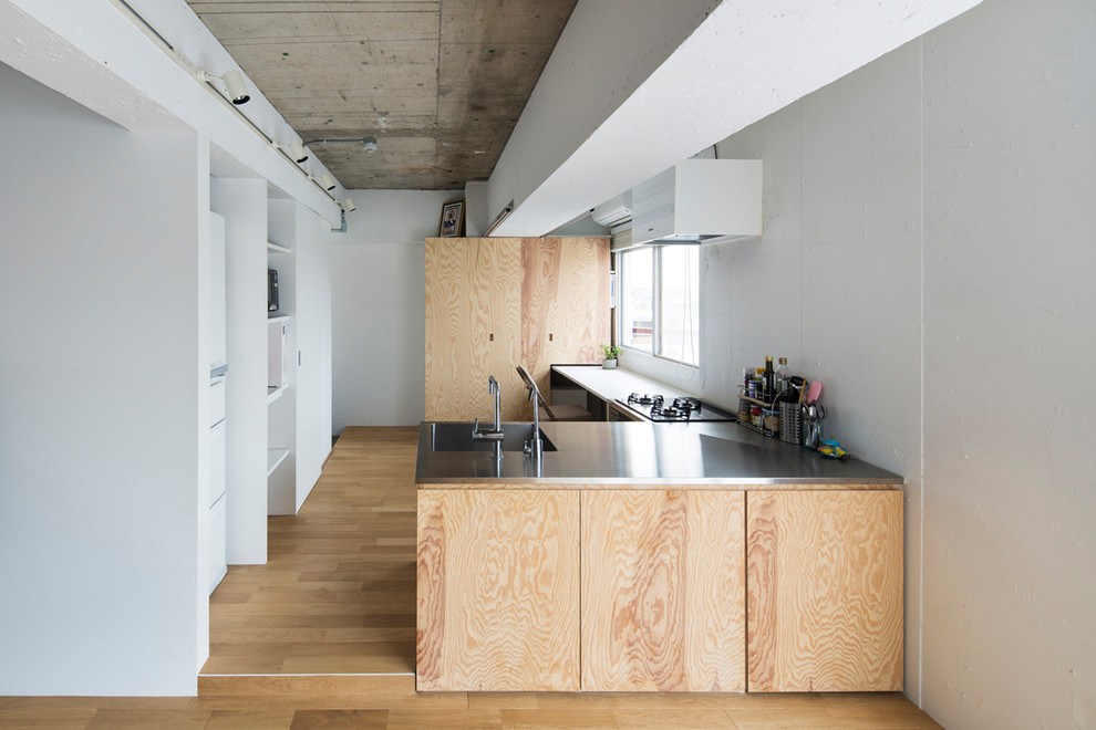 Design ideas for a modern l-shaped eat-in kitchen in Tokyo with flat-panel cabinets, white cabinets, stainless steel benchtops, white splashback, medium hardwood floors, a peninsula and brown floor.
