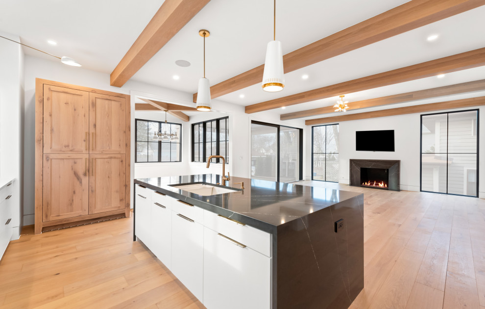 Example of a large transitional u-shaped light wood floor and brown floor open concept kitchen design in Chicago with an undermount sink, flat-panel cabinets, white cabinets, quartz countertops, white backsplash, porcelain backsplash, colored appliances, an island and black countertops