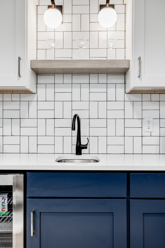This is an example of a mid-sized midcentury single-wall wet bar in Other with an undermount sink, shaker cabinets, blue cabinets, quartzite benchtops, white splashback, porcelain splashback, vinyl floors, brown floor and white benchtop.