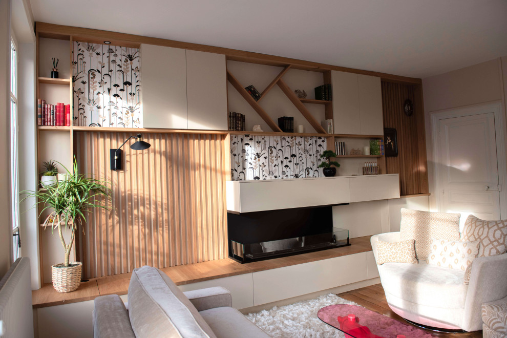 Idee per un piccolo soggiorno tradizionale aperto con libreria, pareti beige, pavimento in legno massello medio e camino bifacciale