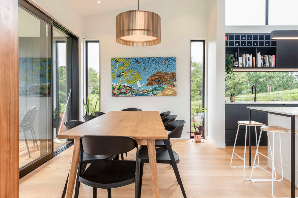Design ideas for a contemporary dining room in Auckland with white walls, light hardwood flooring and beige floors.