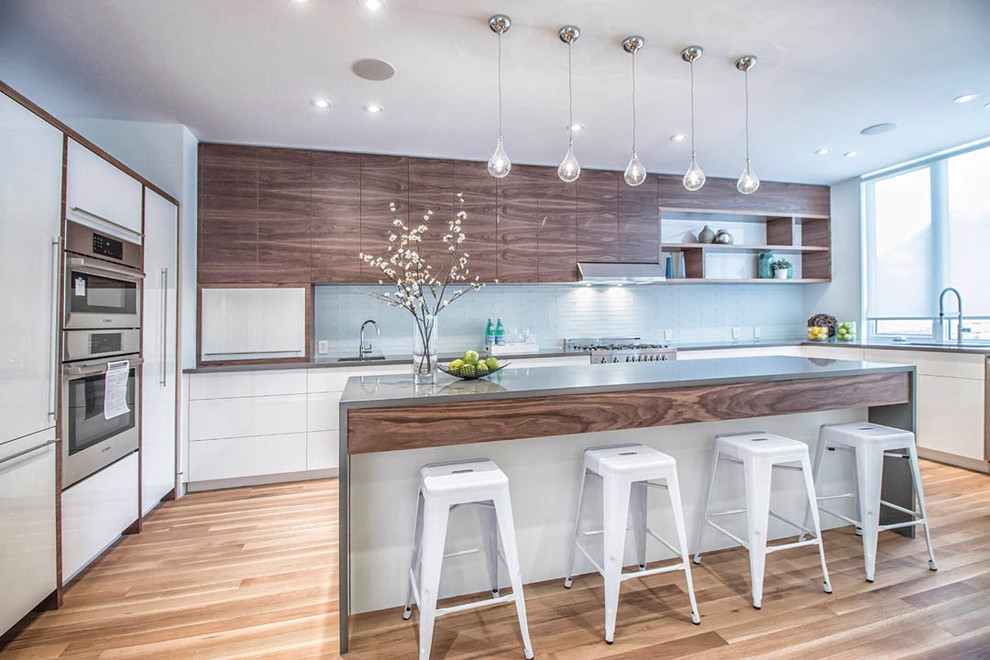 Design ideas for a mid-sized contemporary l-shaped separate kitchen in Toronto with an undermount sink, flat-panel cabinets, white cabinets, concrete benchtops, blue splashback, stainless steel appliances, light hardwood floors, with island and glass tile splashback.