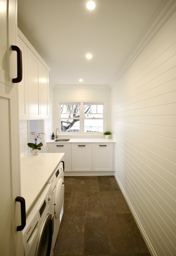Inspiration for a mid-sized transitional u-shaped dedicated laundry room in Sydney with an undermount sink, shaker cabinets, white cabinets, quartz benchtops, white splashback, ceramic splashback, white walls, porcelain floors, a side-by-side washer and dryer and brown floor.