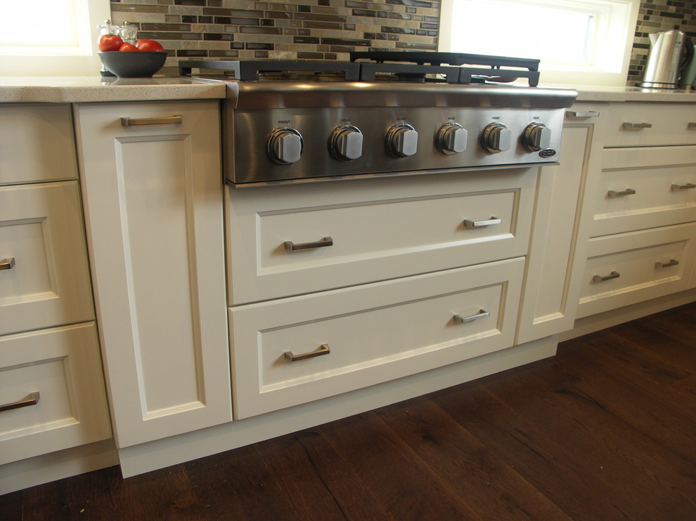 Inspiration for a transitional u-shaped medium tone wood floor kitchen remodel in Edmonton with a farmhouse sink, recessed-panel cabinets, white cabinets, glass tile backsplash, stainless steel appliances and an island