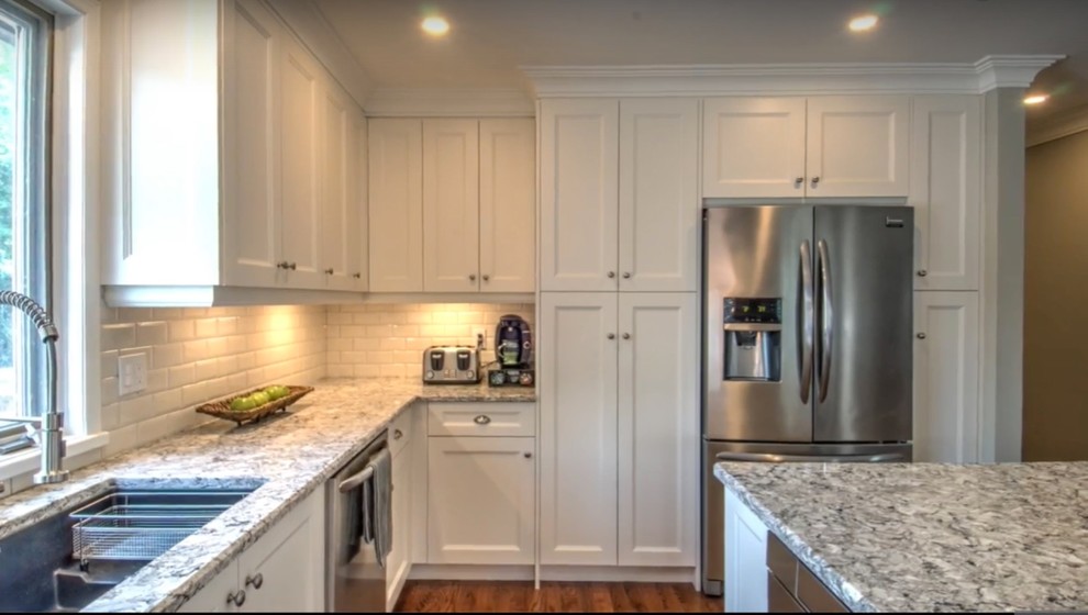 Inspiration for a mid-sized transitional l-shaped medium tone wood floor and brown floor open concept kitchen remodel with an undermount sink, shaker cabinets, white cabinets, white backsplash, stainless steel appliances, an island, quartz countertops and subway tile backsplash