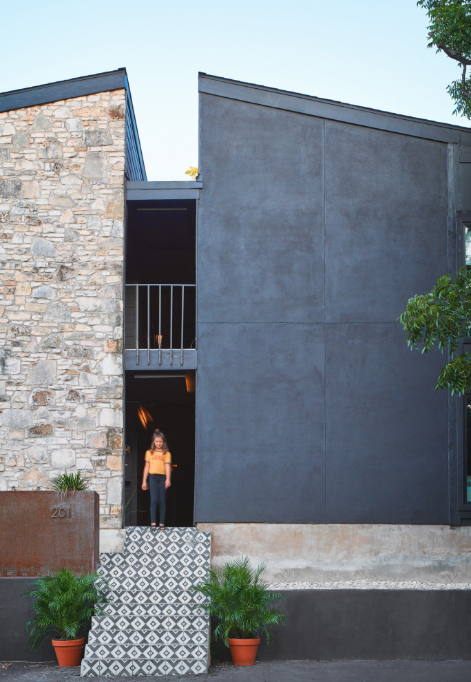 Пример оригинального дизайна: прихожая в современном стиле с черными стенами, бетонным полом, поворотной входной дверью, оранжевой входной дверью и разноцветным полом