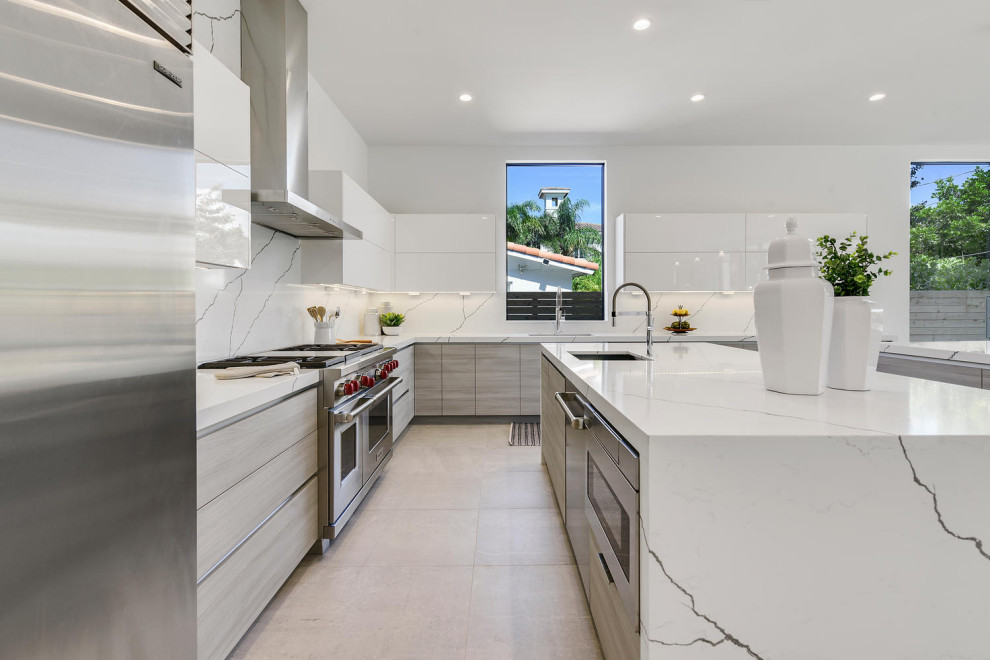 Inspiration for a modern l-shaped kitchen in Miami with a submerged sink, flat-panel cabinets, white cabinets, marble worktops, white splashback, marble splashback, stainless steel appliances, multiple islands, beige floors and white worktops.