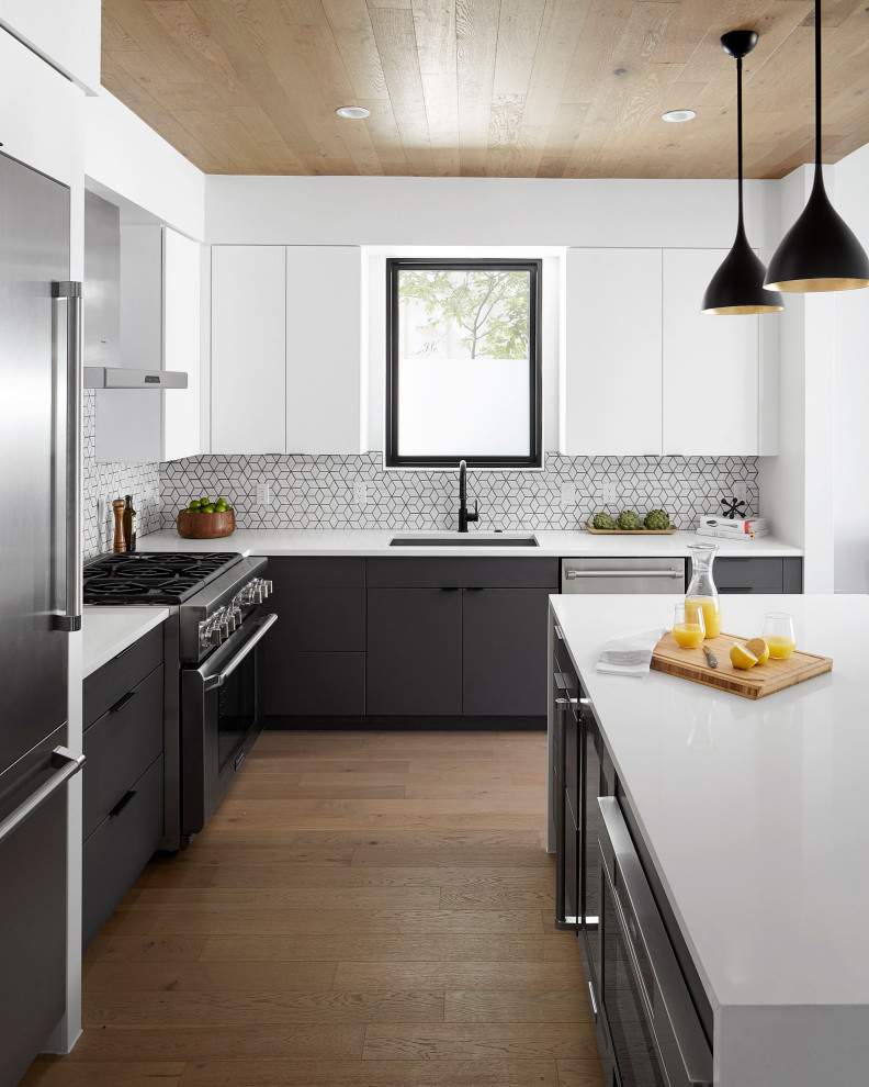 Design ideas for a mid-sized contemporary l-shaped kitchen in Austin with flat-panel cabinets, grey cabinets, quartzite benchtops, white splashback, porcelain splashback, stainless steel appliances, medium hardwood floors, with island, white benchtop, an undermount sink and brown floor.
