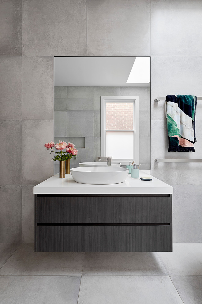Design ideas for a mid-sized contemporary master bathroom in Melbourne with flat-panel cabinets, dark wood cabinets, a freestanding tub, an alcove shower, gray tile, cement tile, grey walls, cement tiles, a console sink, engineered quartz benchtops, grey floor and an open shower.