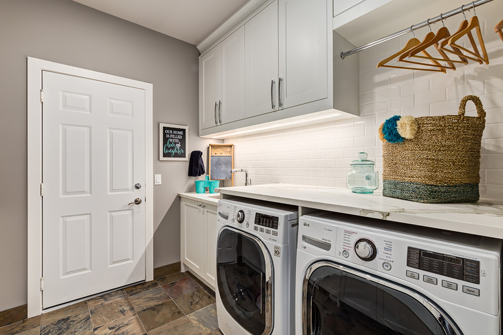 Photo of a large transitional single-wall utility room in Calgary with an undermount sink, flat-panel cabinets, grey cabinets, grey walls, ceramic floors, a side-by-side washer and dryer and quartzite benchtops.