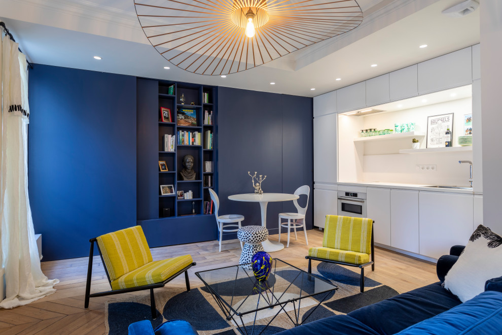 Ispirazione per un soggiorno design di medie dimensioni e aperto con libreria, pareti blu, parquet chiaro, nessun camino, pavimento marrone e soffitto ribassato