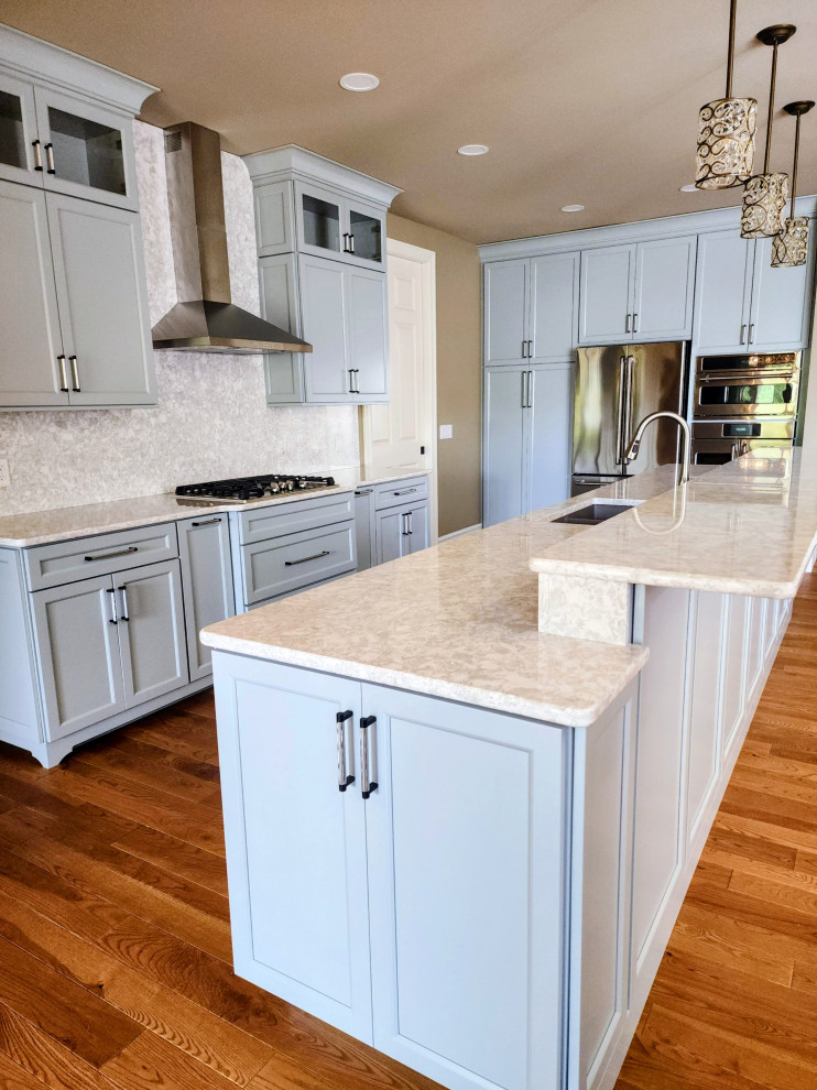 Inspiration for a mid-sized transitional medium tone wood floor and brown floor open concept kitchen remodel with an undermount sink, shaker cabinets, quartz countertops, white backsplash, quartz backsplash, stainless steel appliances, an island and white countertops