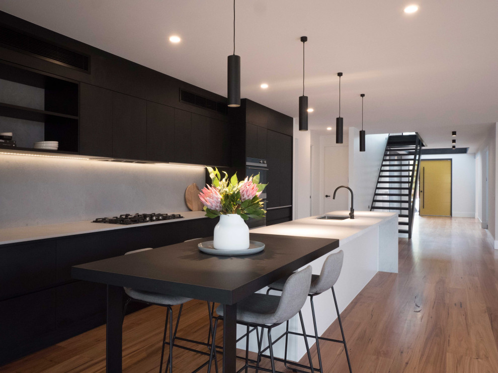 Design ideas for a large contemporary kitchen in Melbourne with an undermount sink, black cabinets, grey splashback, black appliances, medium hardwood floors, with island, brown floor and grey benchtop.