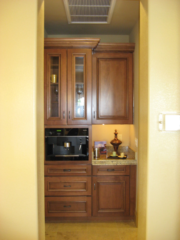 This is an example of a small traditional single-wall wet bar in Las Vegas with raised-panel cabinets, medium wood cabinets, granite benchtops, stone slab splashback and slate floors.