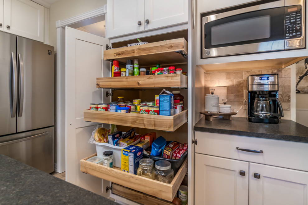 Example of a transitional galley vinyl floor and beige floor eat-in kitchen design with a double-bowl sink, recessed-panel cabinets, white cabinets, granite countertops, beige backsplash, travertine backsplash, stainless steel appliances, a peninsula and black countertops