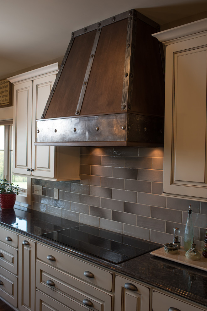 Inspiration for a large rustic l-shaped dark wood floor and brown floor eat-in kitchen remodel with a farmhouse sink, raised-panel cabinets, granite countertops, gray backsplash, ceramic backsplash, black appliances, an island and white cabinets