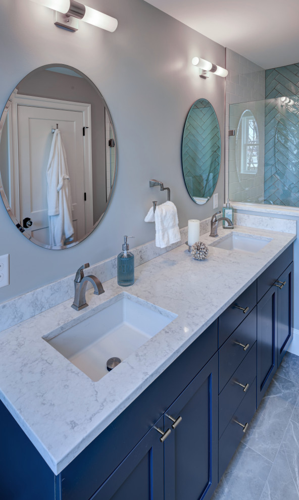 This is an example of a mid-sized transitional master bathroom in DC Metro with shaker cabinets, blue cabinets, an alcove shower, a one-piece toilet, blue tile, ceramic tile, white walls, porcelain floors, an undermount sink, engineered quartz benchtops, grey floor, a hinged shower door, white benchtops, a shower seat, a double vanity and a freestanding vanity.