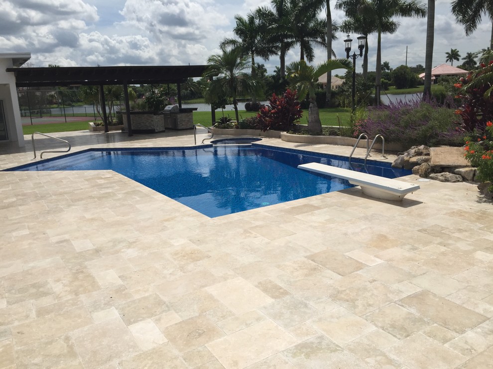 Photo of a backyard pool in Miami with a pool house and natural stone pavers.