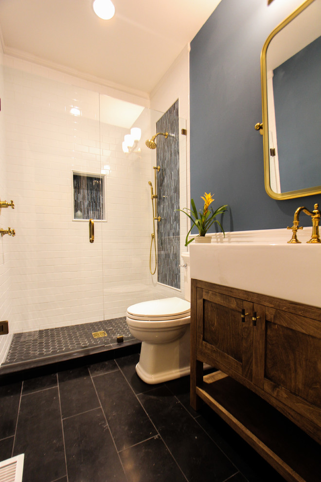 Design ideas for a mid-sized arts and crafts 3/4 bathroom in Atlanta with shaker cabinets, a two-piece toilet, blue tile, white tile, ceramic tile, blue walls, limestone floors, an integrated sink, solid surface benchtops, black floor and a hinged shower door.