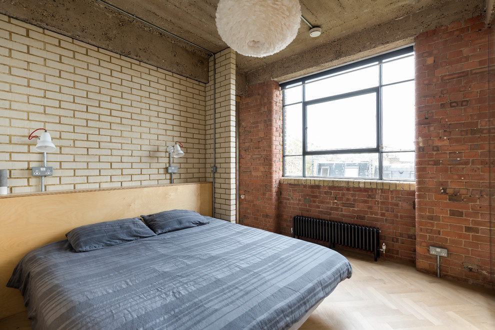 This is an example of an industrial bedroom in London with white walls, light hardwood floors and beige floor.