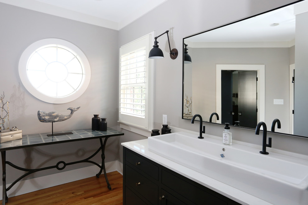 Photo of a mid-sized industrial master bathroom in Raleigh with recessed-panel cabinets, black cabinets, an alcove shower, black and white tile, subway tile, grey walls, medium hardwood floors, a vessel sink, engineered quartz benchtops, a two-piece toilet, orange floor, a hinged shower door and white benchtops.