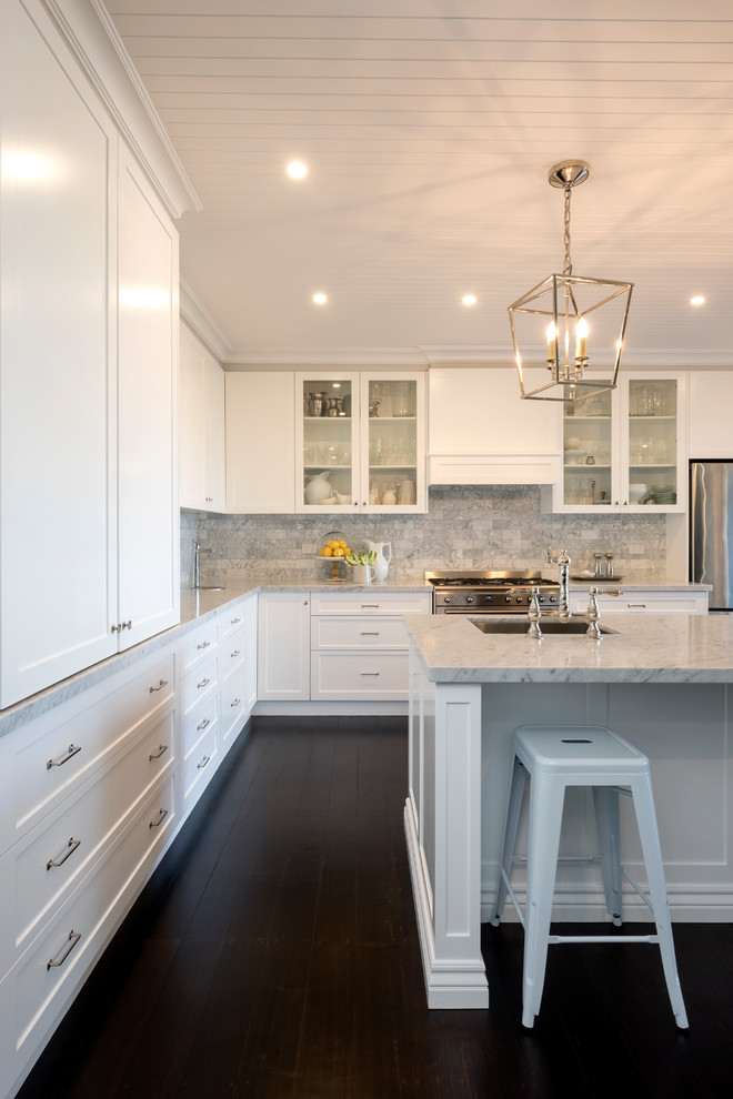 Transitional l-shaped kitchen in Melbourne with an undermount sink, shaker cabinets, white cabinets, grey splashback, stainless steel appliances, dark hardwood floors, with island, brown floor and white benchtop.