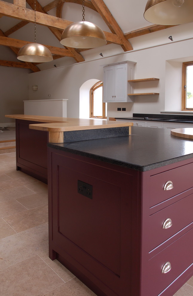 Inspiration for a large arts and crafts eat-in kitchen in Wiltshire with flat-panel cabinets, granite benchtops, limestone floors and with island.