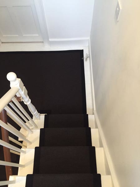 Photo of a mid-sized contemporary carpeted u-shaped staircase in London with wood railing.