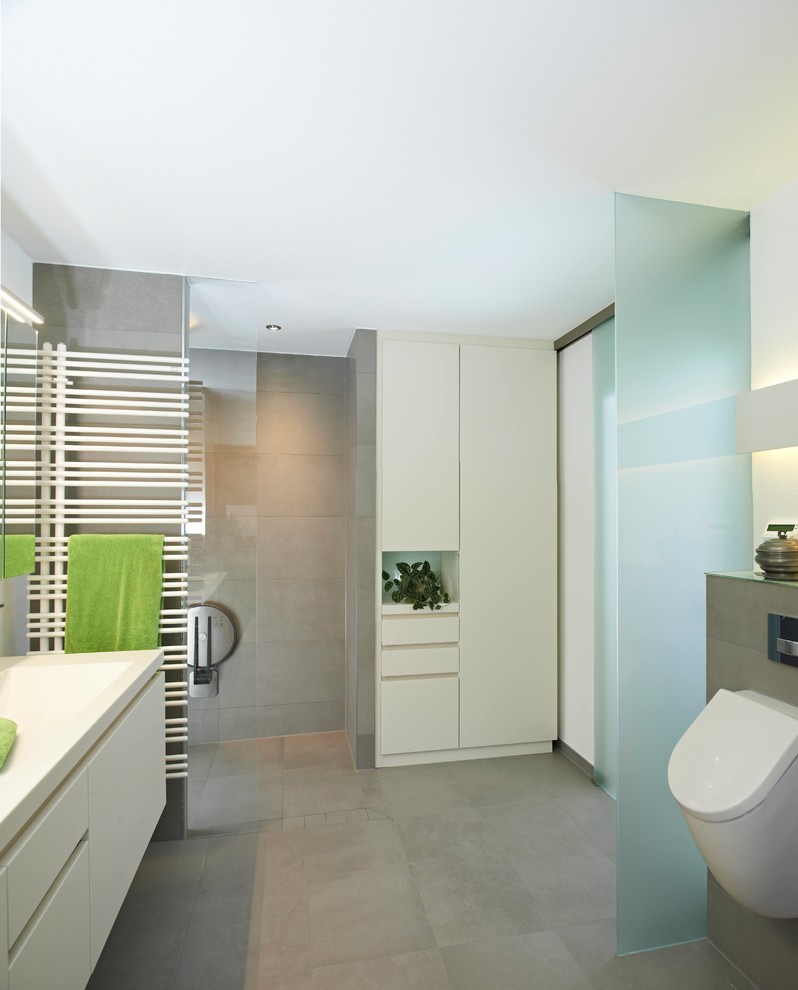 This is an example of a mid-sized contemporary 3/4 bathroom in Stuttgart with flat-panel cabinets, white cabinets, an open shower, an urinal, gray tile, cement tile, white walls, cement tiles, an integrated sink, grey floor and an open shower.