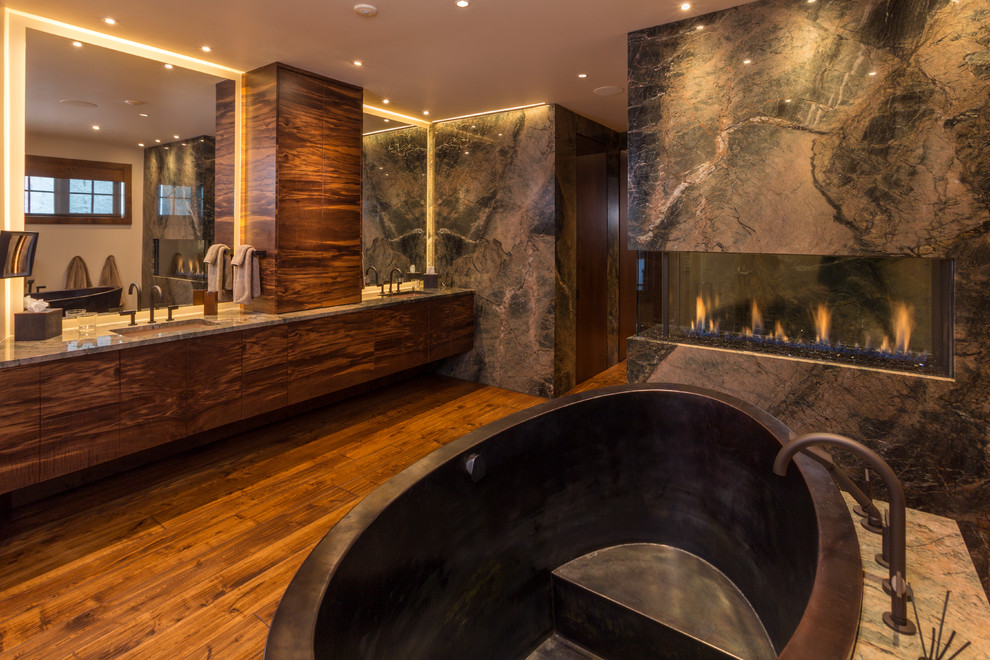 Large trendy master medium tone wood floor freestanding bathtub photo in Denver with flat-panel cabinets, dark wood cabinets, an undermount sink and granite countertops