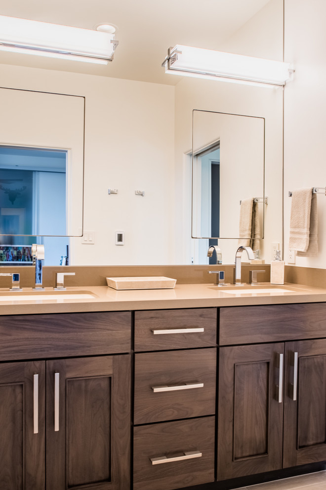 Example of a mid-sized mountain style 3/4 porcelain tile and beige floor tub/shower combo design in Phoenix with shaker cabinets, dark wood cabinets, beige walls, an undermount sink, solid surface countertops and beige countertops
