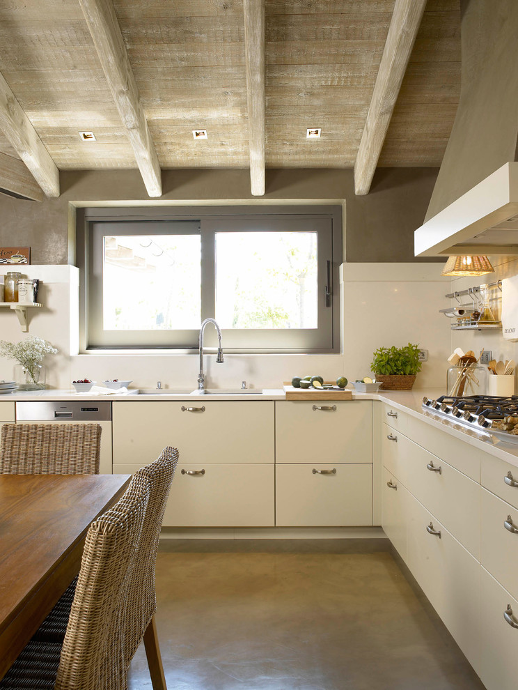 Inspiration for a country eat-in kitchen in Barcelona with a double-bowl sink, flat-panel cabinets, white cabinets, white splashback, stainless steel appliances, concrete floors and no island.