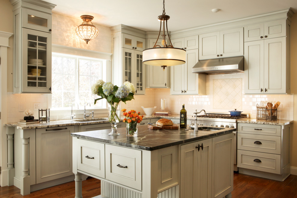 Inspiration for a mid-sized traditional u-shaped open plan kitchen in St Louis with soapstone benchtops, recessed-panel cabinets, white splashback, subway tile splashback, stainless steel appliances, an undermount sink, grey cabinets, medium hardwood floors and with island.