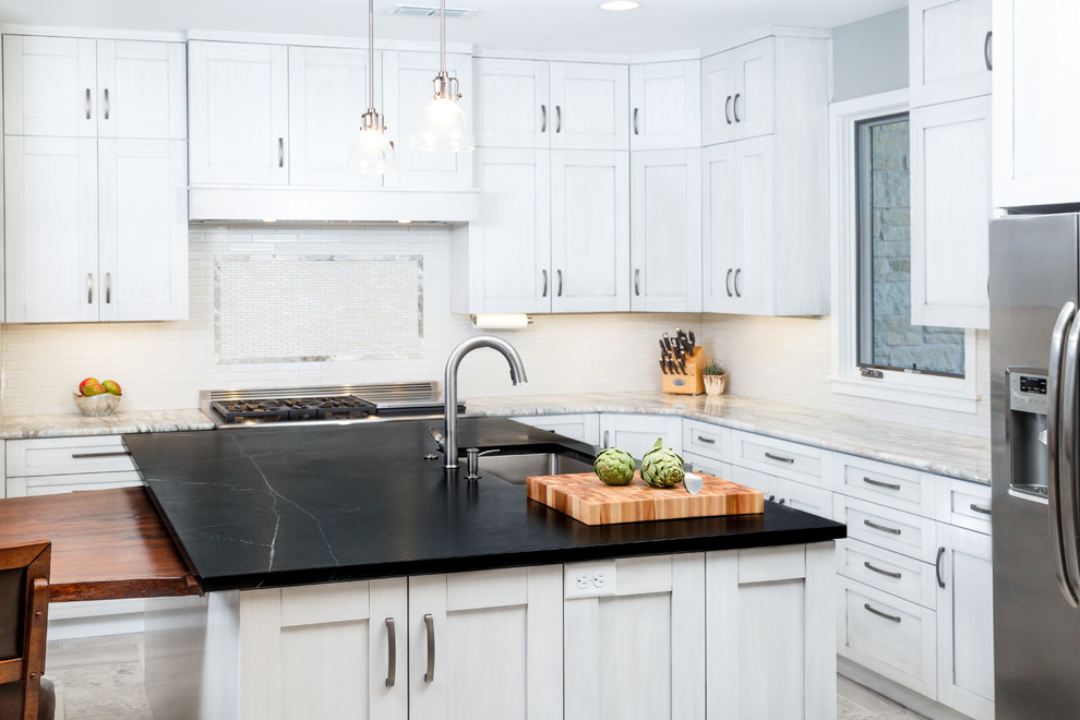 Inspiration for a large transitional l-shaped porcelain tile eat-in kitchen remodel in Austin with a single-bowl sink, shaker cabinets, gray cabinets, soapstone countertops, white backsplash, ceramic backsplash, stainless steel appliances and an island