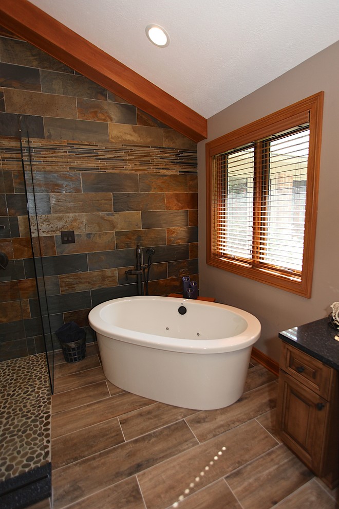 Freestanding bathtub - large rustic master slate tile brown floor freestanding bathtub idea in Indianapolis with brown cabinets, beige walls and an undermount sink