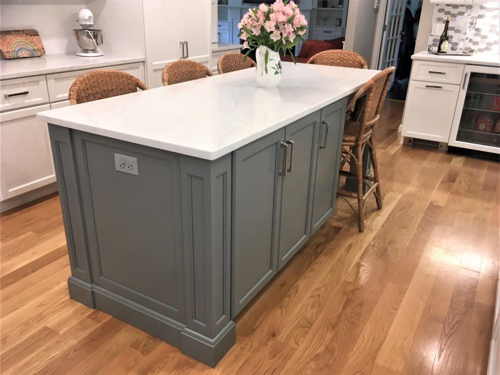 Example of a large transitional galley light wood floor and brown floor eat-in kitchen design in Boston with an undermount sink, shaker cabinets, white cabinets, quartz countertops, white backsplash, subway tile backsplash, stainless steel appliances, two islands and white countertops