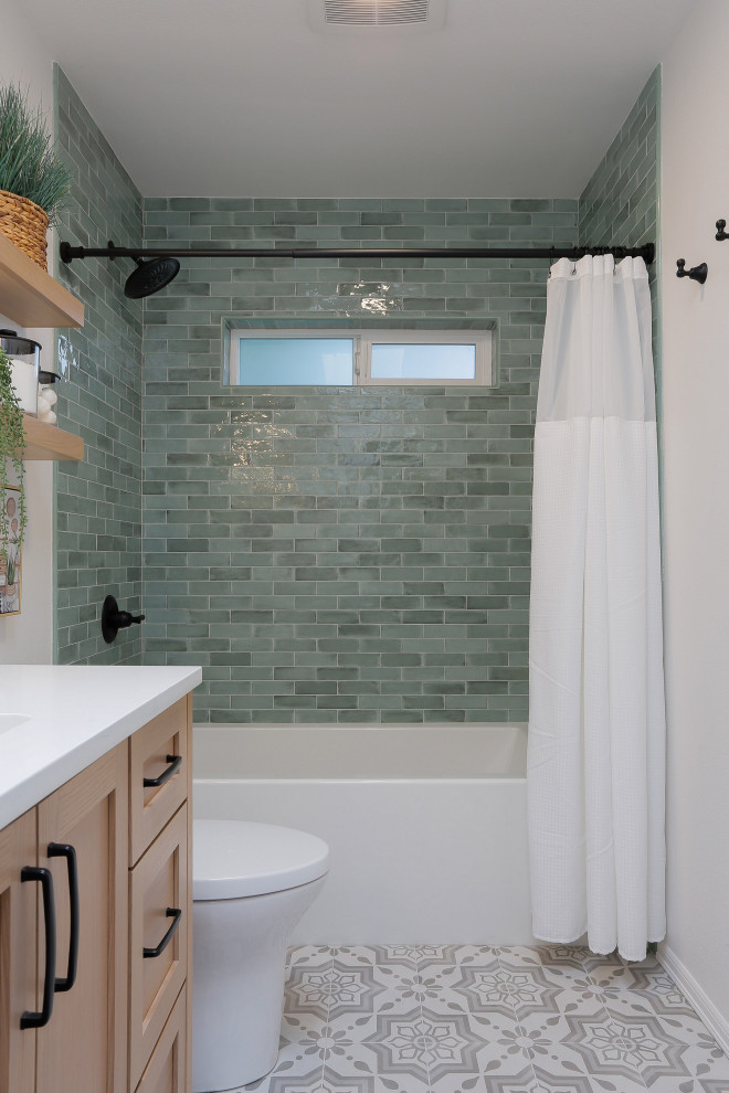 Medium sized coastal family bathroom in Seattle with shaker cabinets, light wood cabinets, an alcove bath, a shower/bath combination, a one-piece toilet, green tiles, metro tiles, white walls, porcelain flooring, a submerged sink, engineered stone worktops, grey floors, a shower curtain, white worktops, a wall niche, double sinks and a built in vanity unit.