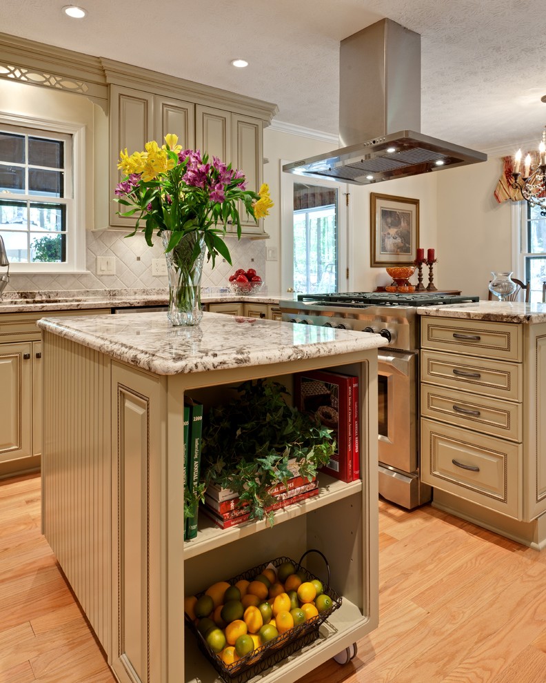 Inspiration for a mid-sized traditional u-shaped eat-in kitchen in Atlanta with raised-panel cabinets, an undermount sink, green cabinets, granite benchtops, beige splashback, stone tile splashback, stainless steel appliances, light hardwood floors, with island, brown floor and beige benchtop.