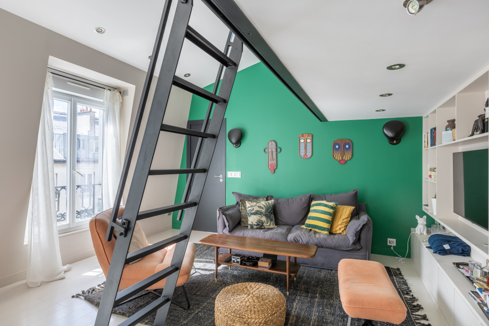 Идея дизайна: открытая гостиная комната среднего размера в стиле фьюжн с с книжными шкафами и полками, зелеными стенами, деревянным полом, стандартным камином, фасадом камина из штукатурки, мультимедийным центром и белым полом