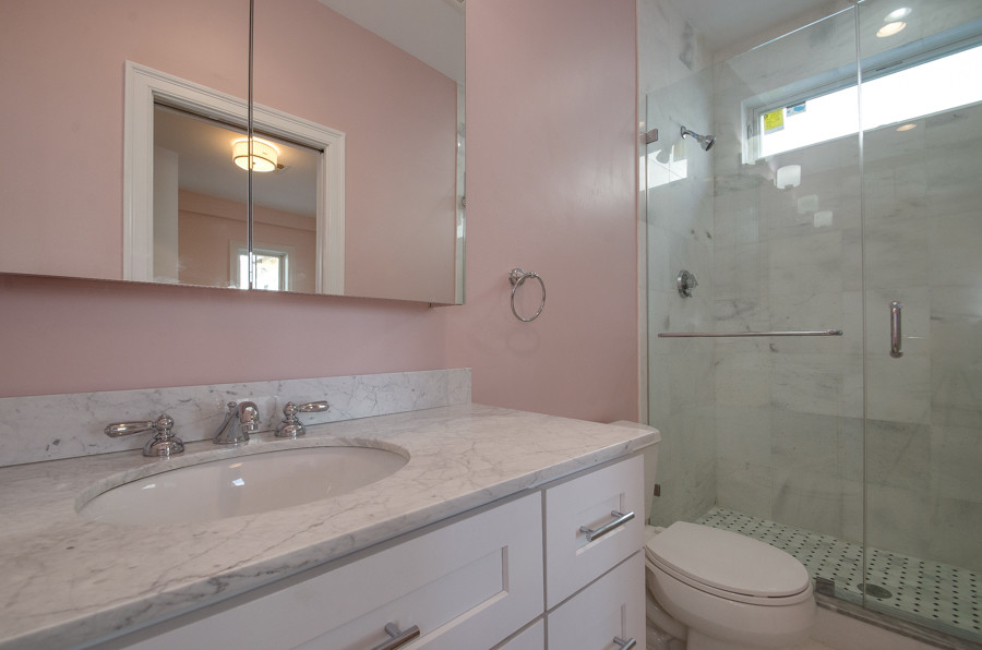Double shower - large 3/4 white tile double shower idea in Boston with recessed-panel cabinets, white cabinets, a one-piece toilet, pink walls, an undermount sink and quartz countertops