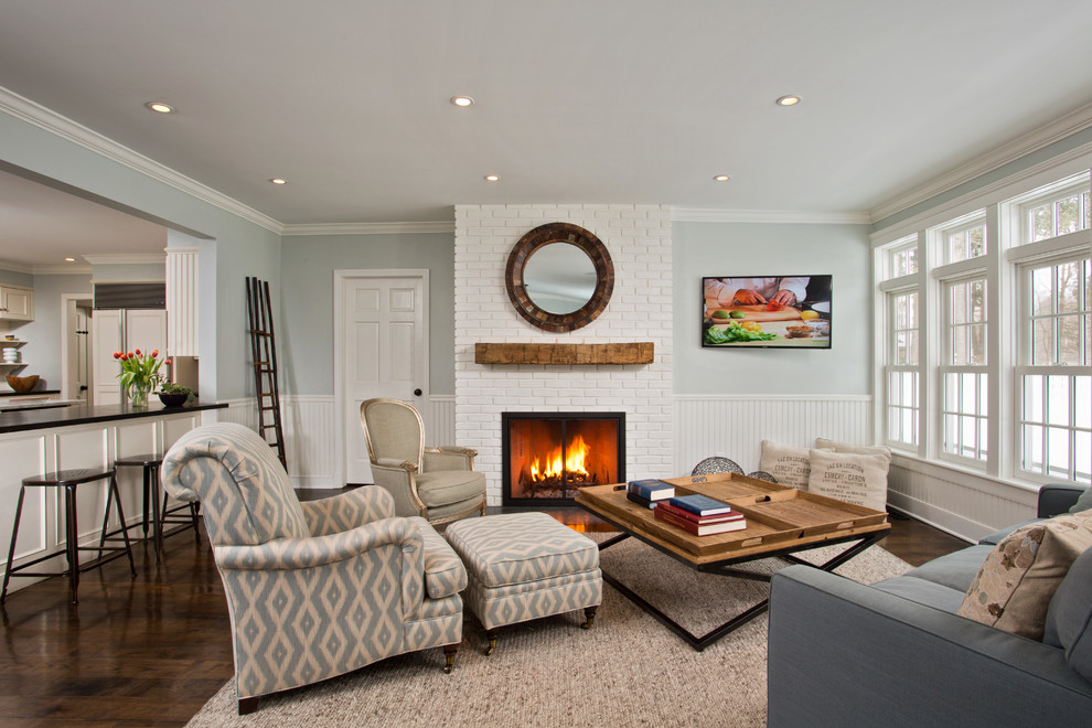 This is an example of a mid-sized transitional open concept family room in Boston with dark hardwood floors, a standard fireplace, a wall-mounted tv, blue walls and a brick fireplace surround.
