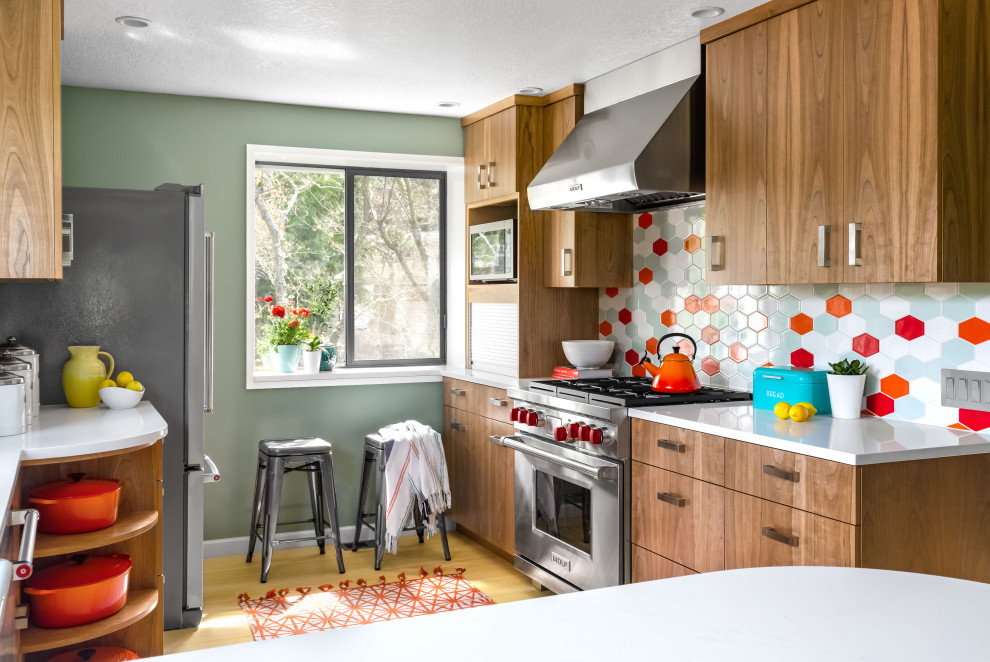 Inspiration for a midcentury kitchen in Seattle with flat-panel cabinets, medium wood cabinets, multi-coloured splashback, stainless steel appliances, light hardwood floors, a peninsula, beige floor and white benchtop.