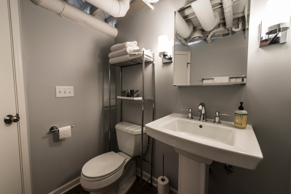Mid-sized transitional 3/4 bathroom in Milwaukee with an alcove shower, a two-piece toilet, grey walls, dark hardwood floors and a pedestal sink.