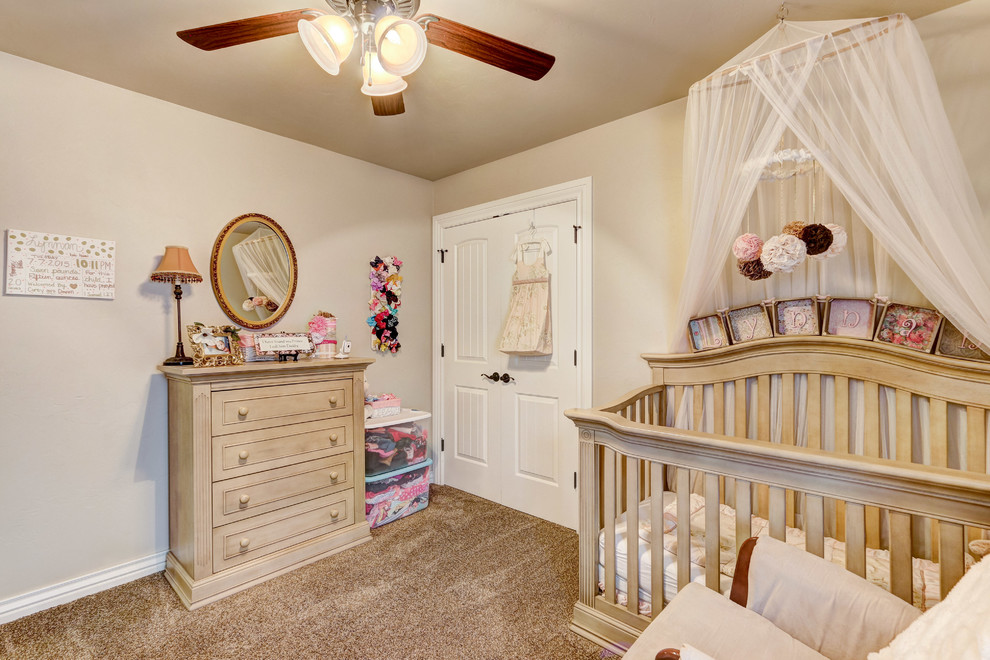 This is an example of a mid-sized transitional nursery for girls in Oklahoma City with beige walls, carpet and brown floor.